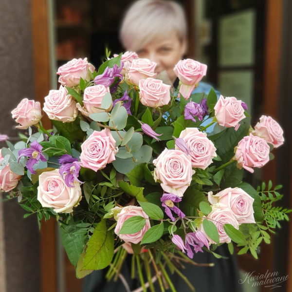 Florystka z Kwiaciarni Internetowej Poczta Kwiatowa trzyma w rękach bukiet różowych róż