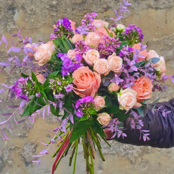Bukiet 'Sonata Świtu' z różami, fioletowymi i błękitnymi kwiatami na drewnianym tle.